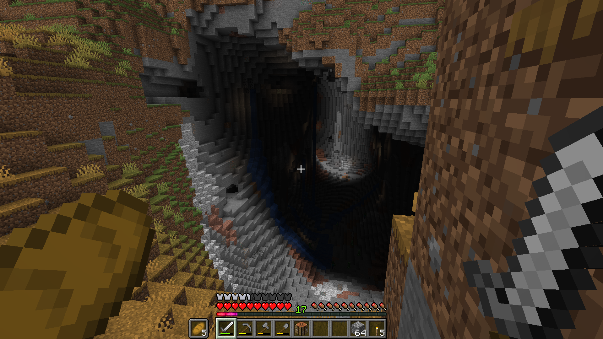 Blick in eine große, offene Höhle an der Seite eines Hügels. Im hinteren Bereich fällt Sonnenlicht durch ein Loch in der Decke auf einen großen Stalagmit.